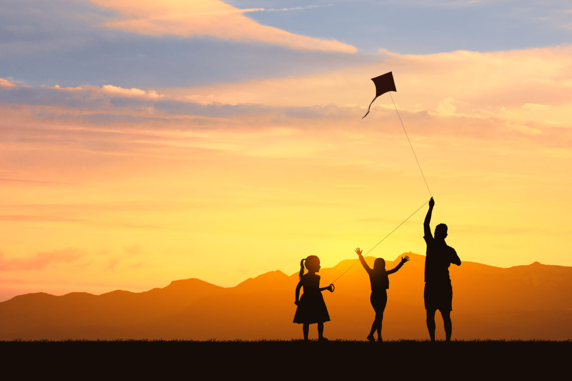 Familie lässt im Sonnenuntergang einen Drachen steigen